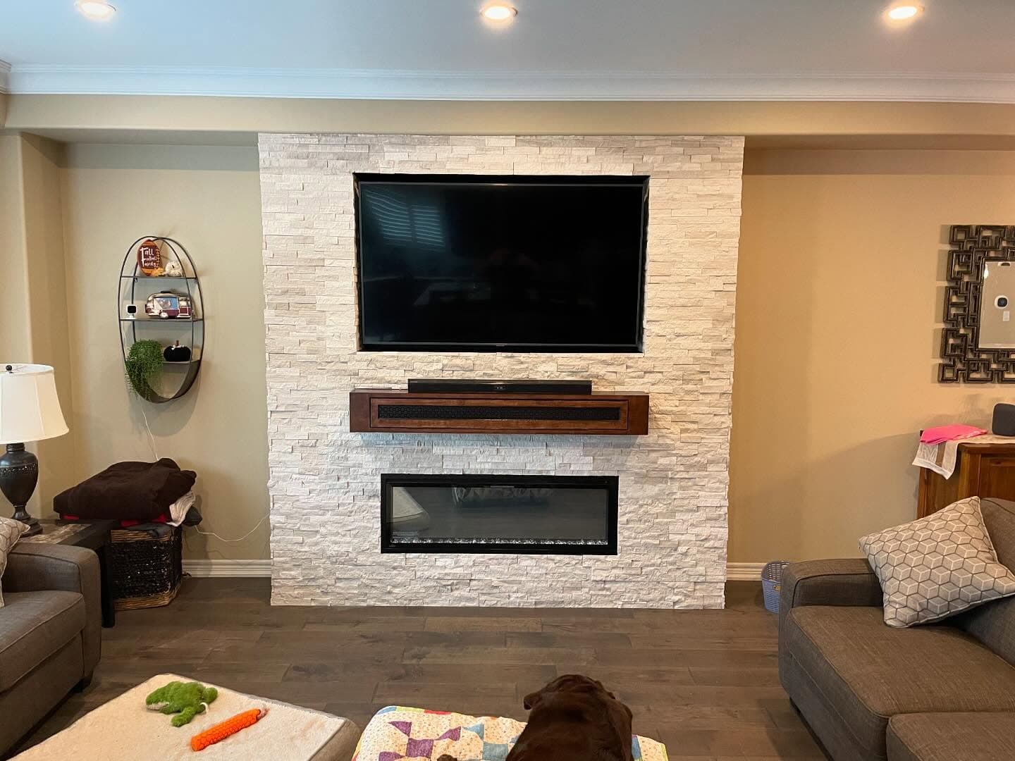 Stacked-stone fireplace feature wall with mounted TV and floating mantel