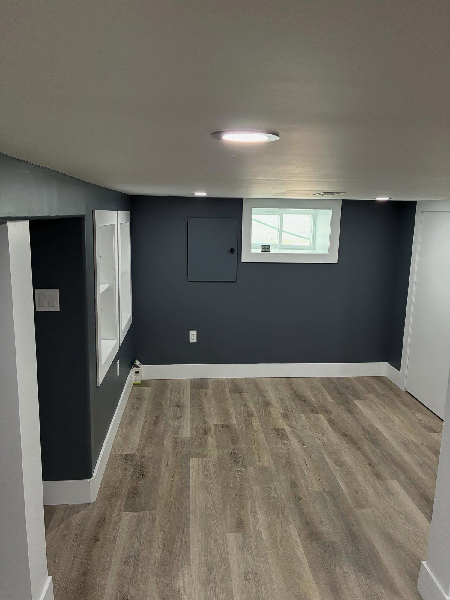 Finished basement with navy feature wall and luxury vinyl plank flooring