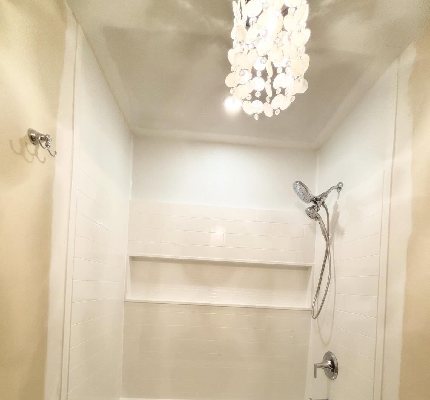 Renovated bathroom with white subway tile surround and recessed shelf