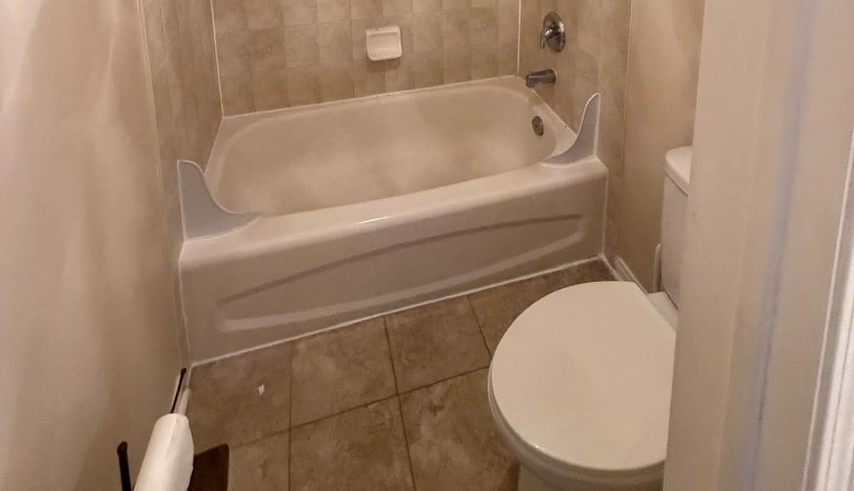 Bathroom before renovation with a dated beige tub and tile